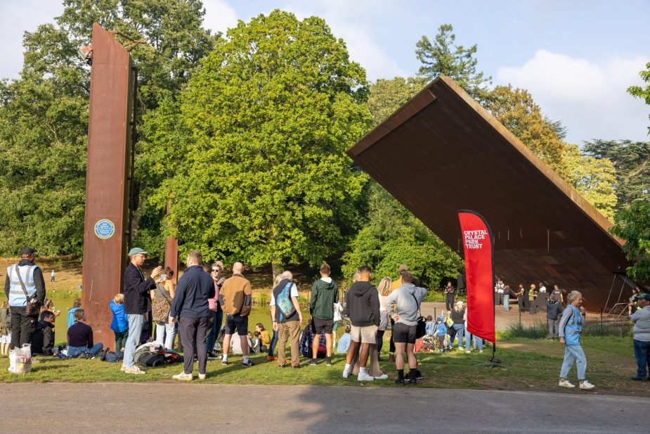 CPPT_Handover_Festival (157 of 164) A group of over 20 people of a range of ages stood and sat by the Concert Platform in Crystal Palace Park at a party to celebrate the handover of the park to the Crystal Palace Park Trust.